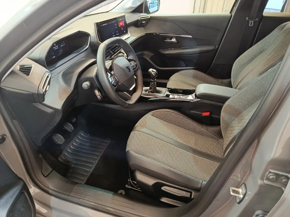 Intérieur avant droit de la Peugeot 208 PureTech 100 S&S Allure gris foncé, volant cuir et écran tactile visible
