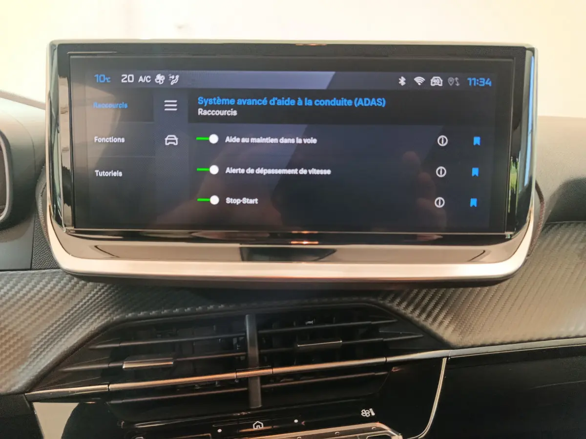 Écran tactile central affichant les aides à la conduite dans l'habitacle noir de la Peugeot 208 PureTech 100 S&S Allure.