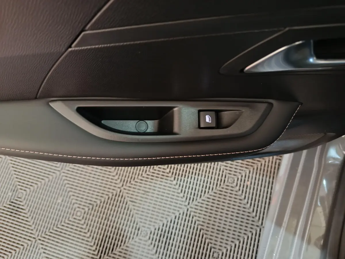 Poignée intérieure côté gauche de porte en cuir noir avec bouton de verrouillage sur Peugeot 208 gris foncé 2025.