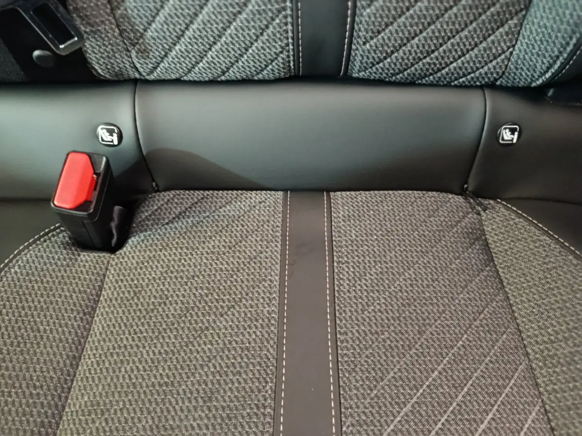Gros plan sur la banquette arrière gris foncé de la Peugeot 208 avec ceinture de sécurité rouge et fixations Isofix visibles.