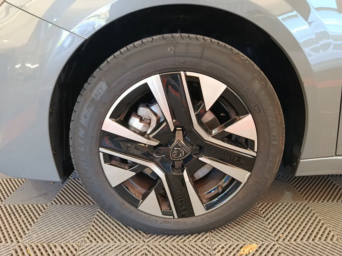 Gros plan sur la roue avant gauche gris foncé d'une Peugeot 208 PureTech 100 S&S Allure avec jante alliage noire et argent.