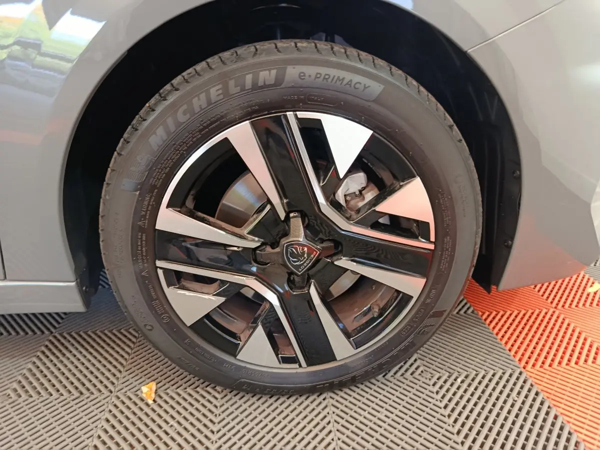 Gros plan sur la roue avant droite de la Peugeot 208 gris foncé avec jante alliage noire et argentée au design moderne.