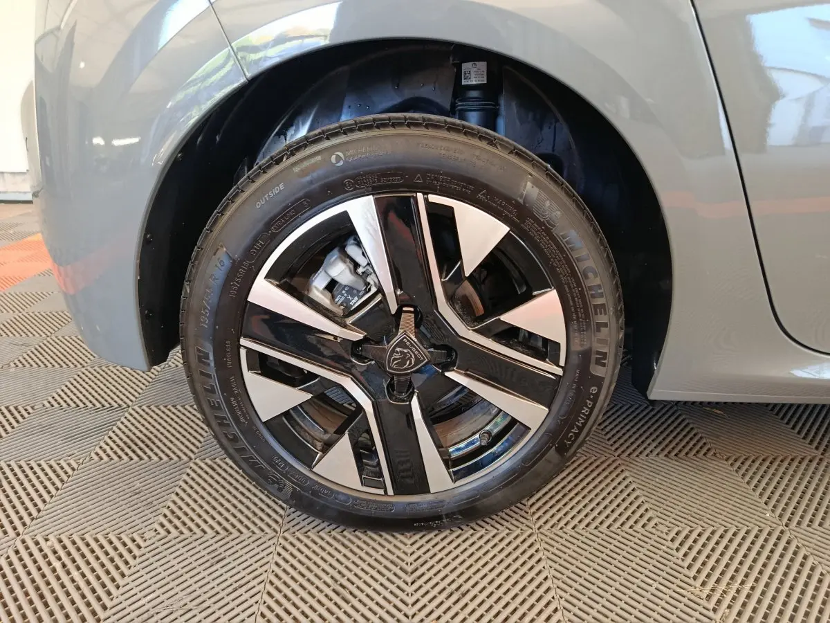 Gros plan sur la roue avant gauche grise d'une Peugeot 208 PureTech 100 S&S Allure avec jante alliage bicolore.