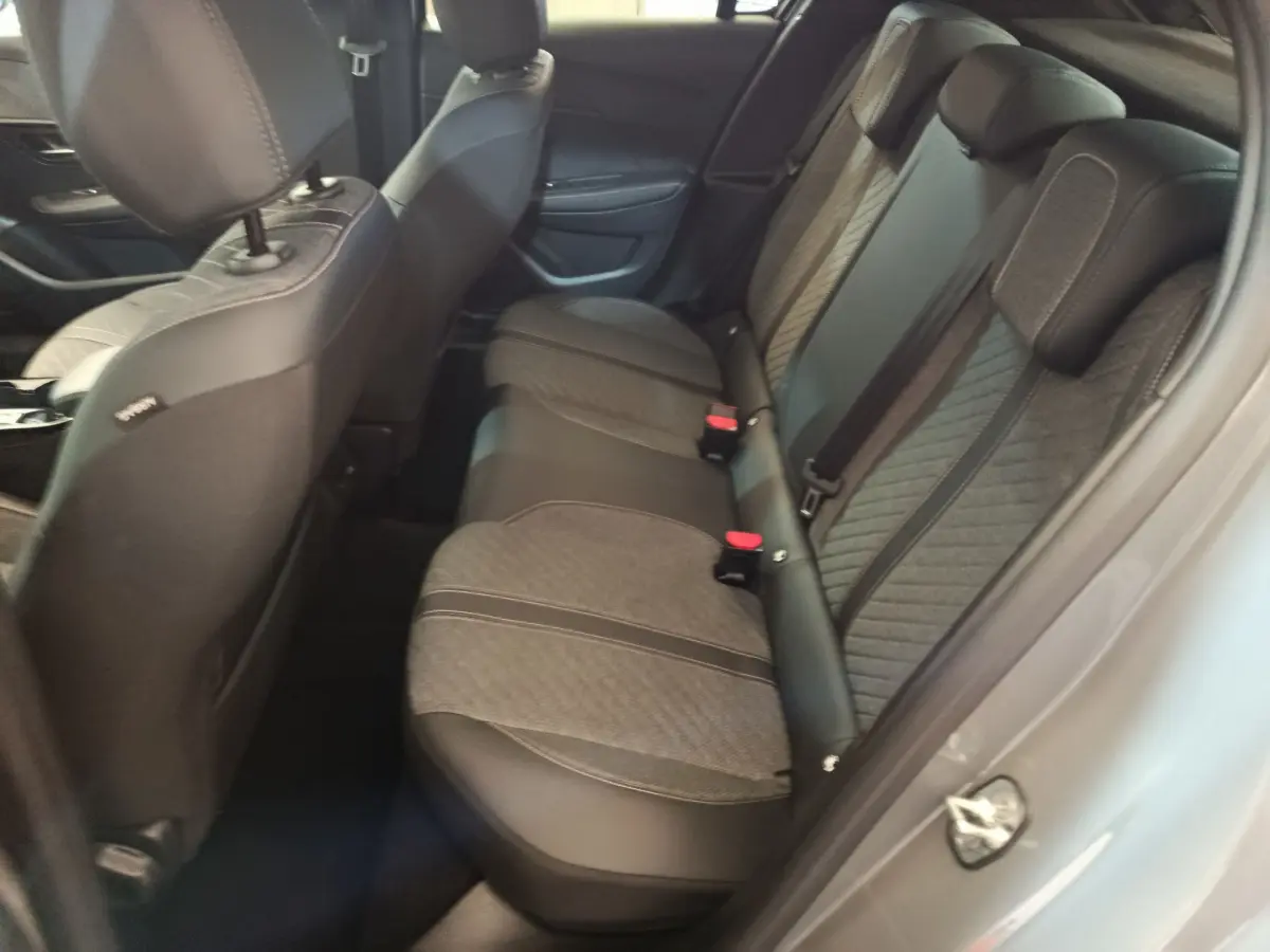 Vue côté droit de l'intérieur arrière de la Peugeot 208 gris foncé avec sièges tissu et cuir bicolores.