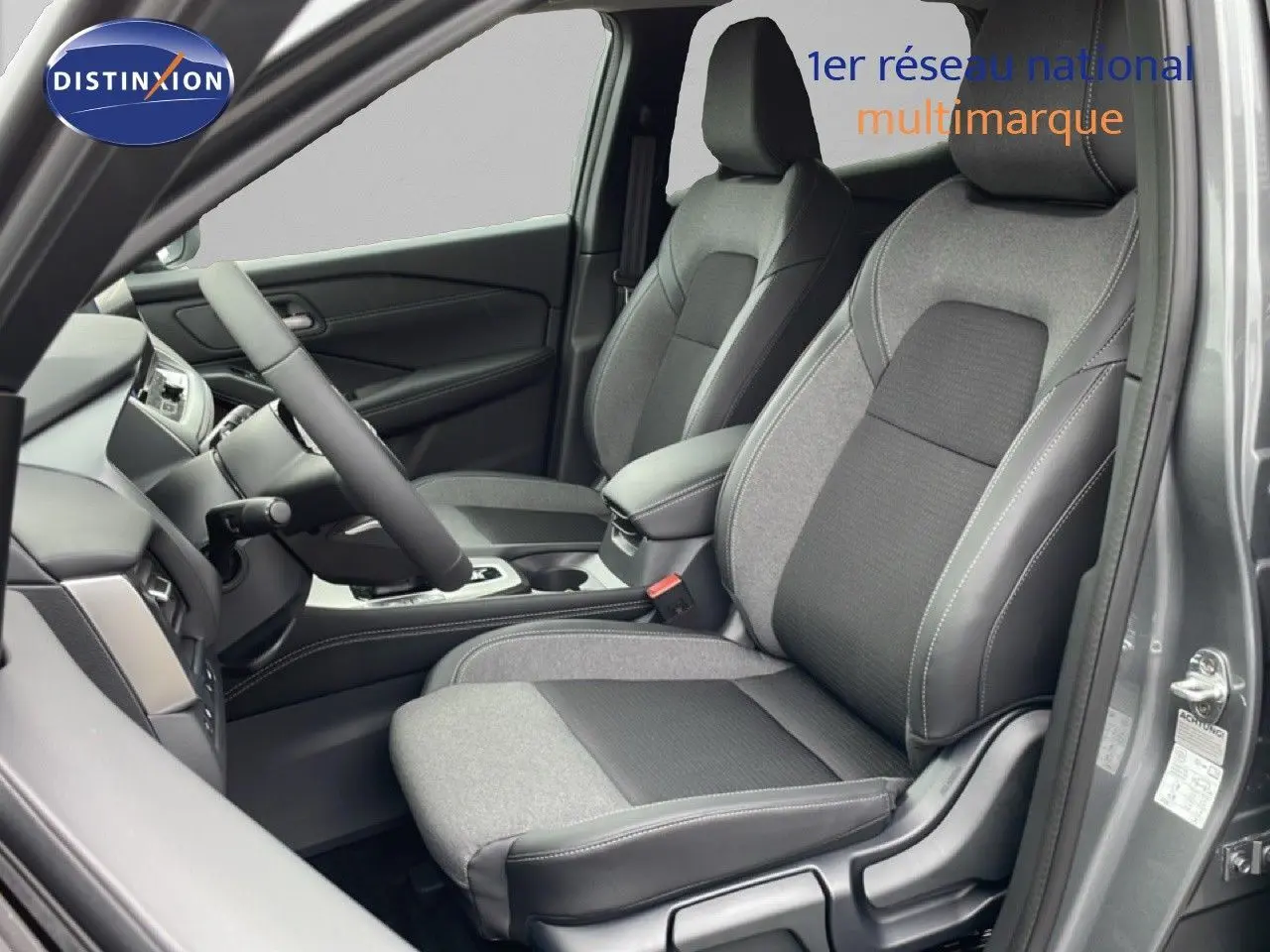 Vue intérieure côté conducteur du Nissan Qashqai gris squale métal, avec sièges bi-matière tissu et cuir noir.