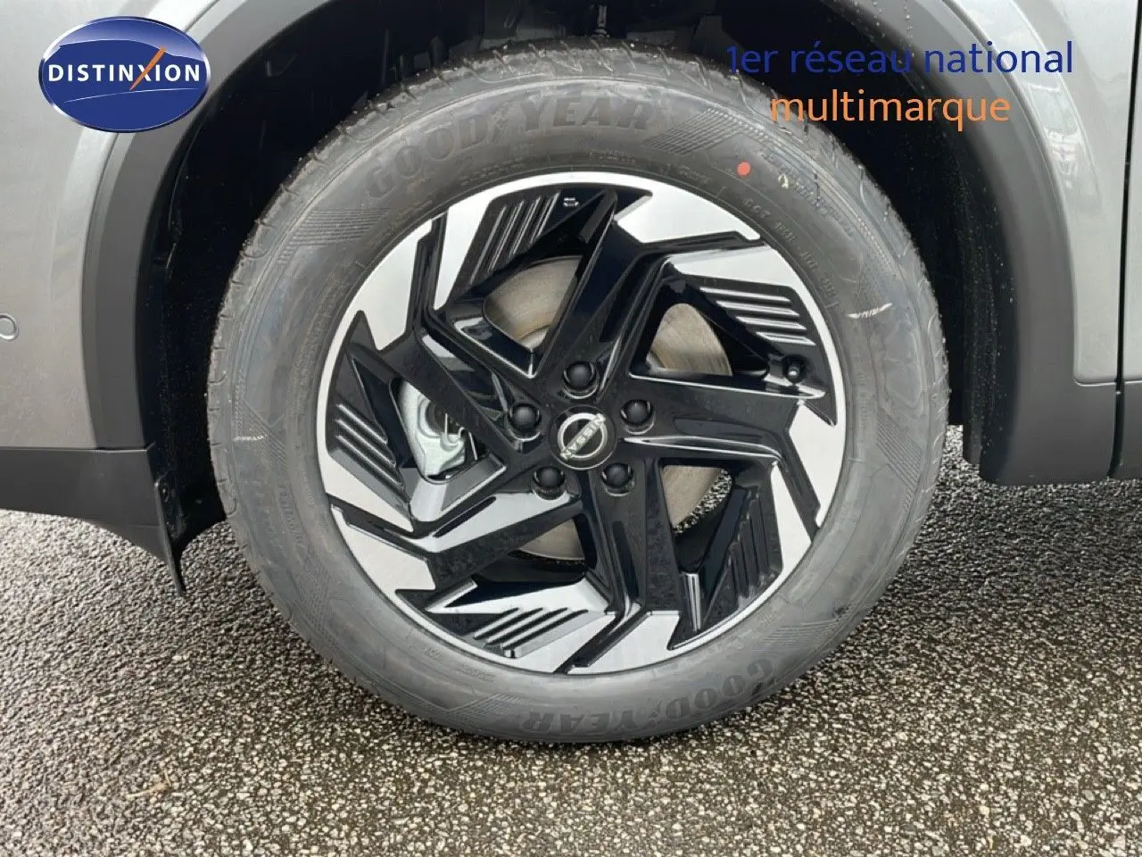 Gros plan sur la roue avant droite du Nissan Qashqai gris squale métal, jante alliage noire et argentée au design moderne.