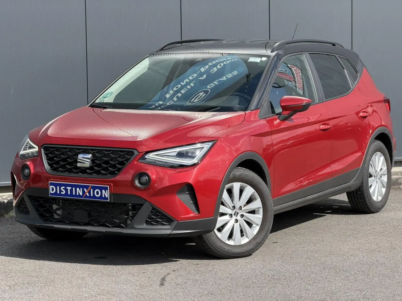 SEAT Arona Rouge Désir en 3/4 avant droit, toit noir contrasté et jantes alliage 16 pouces visibles.