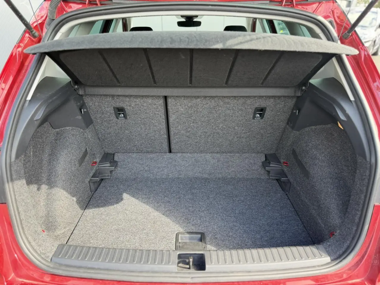 Coffre ouvert vu de l'arrière d'un SEAT Arona Rouge Désir, montrant un espace de rangement propre et spacieux.
