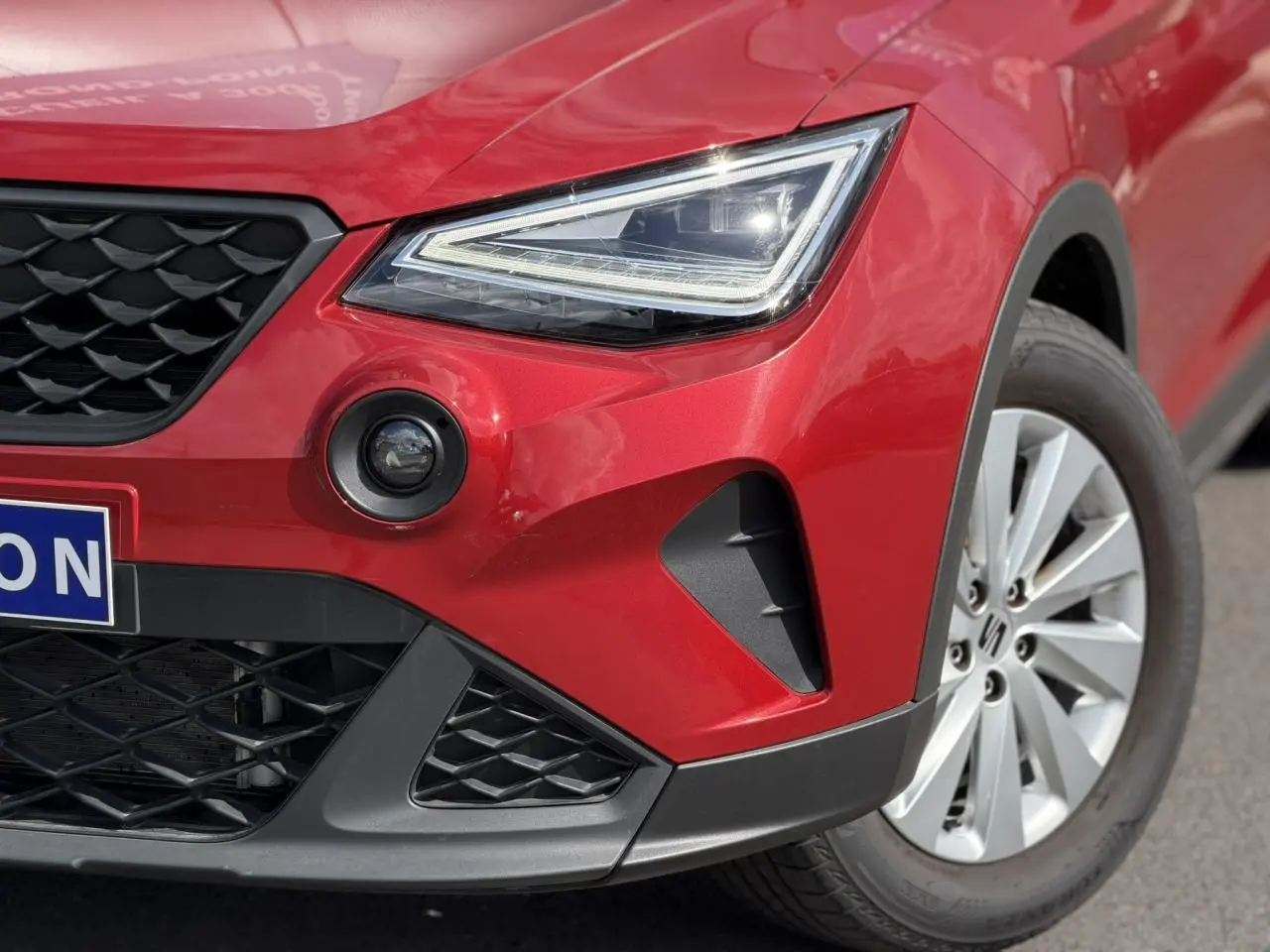 Gros plan sur l'avant droit du SEAT Arona Rouge Désir, mettant en valeur le phare LED et la jante alliage 16 pouces.