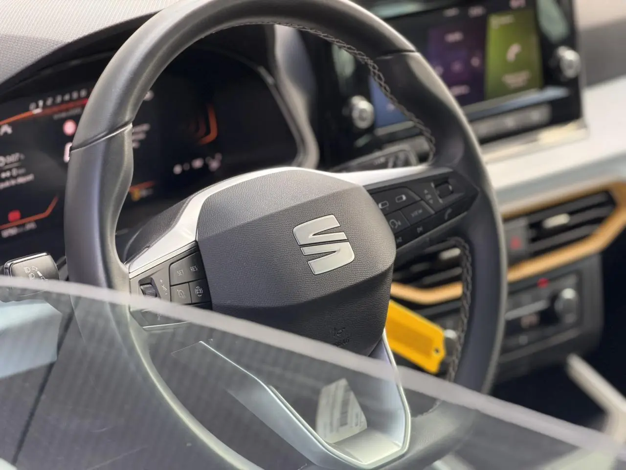 Gros plan sur le volant et le tableau de bord digital du SEAT Arona 2025, avec détails en noir et inserts bois clair.