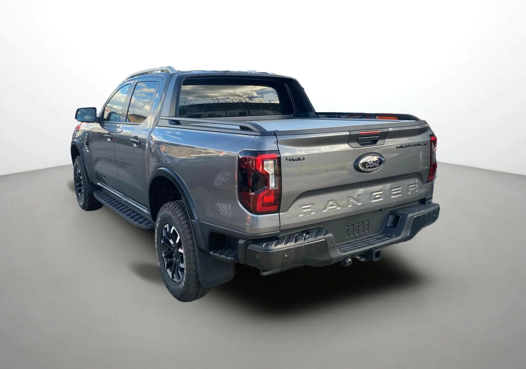 Ford Ranger 205 Wildtrak gris carbone vu en 3/4 arrière droit avec rideau de benne et jantes noires.