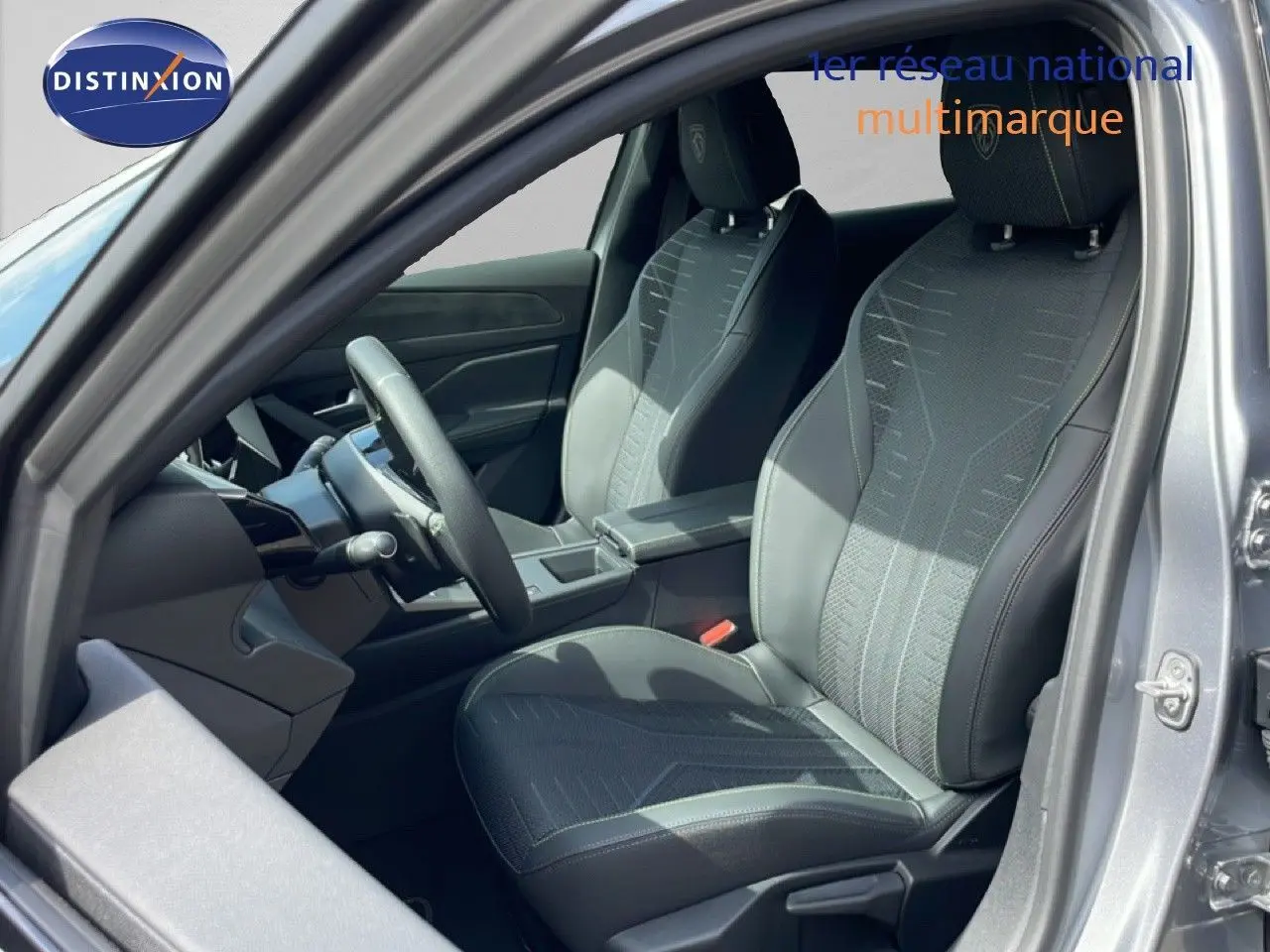 Vue intérieure côté conducteur de la Peugeot 308 gris Artense, sièges noirs avec surpiqûres contrastées.