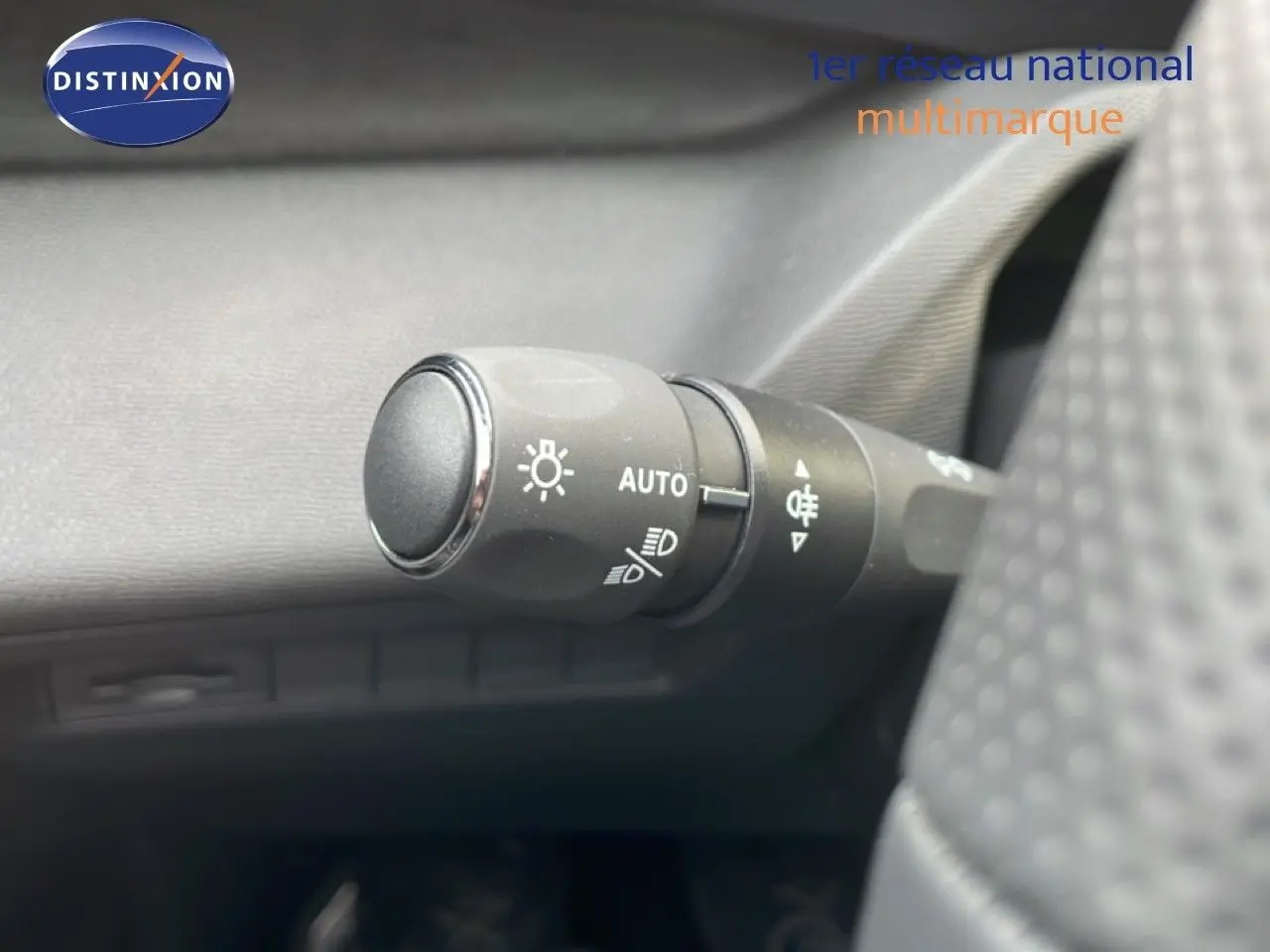 Gros plan sur la commande des phares automatiques à gauche du volant dans l’habitacle d’une Peugeot 308 gris Artense.