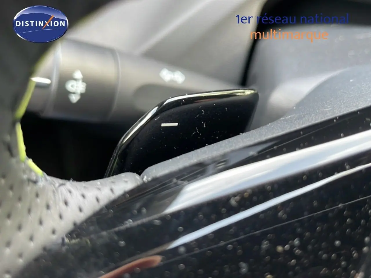 Gros plan sur la palette de changement de vitesse noire du volant perforé d’une Peugeot 308 gris Artense 2026.
