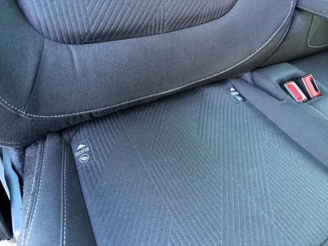 Gros plan sur l'assise arrière noire du Nissan Primastar 2025, montrant les fixations ISOFIX et les ceintures rouges.