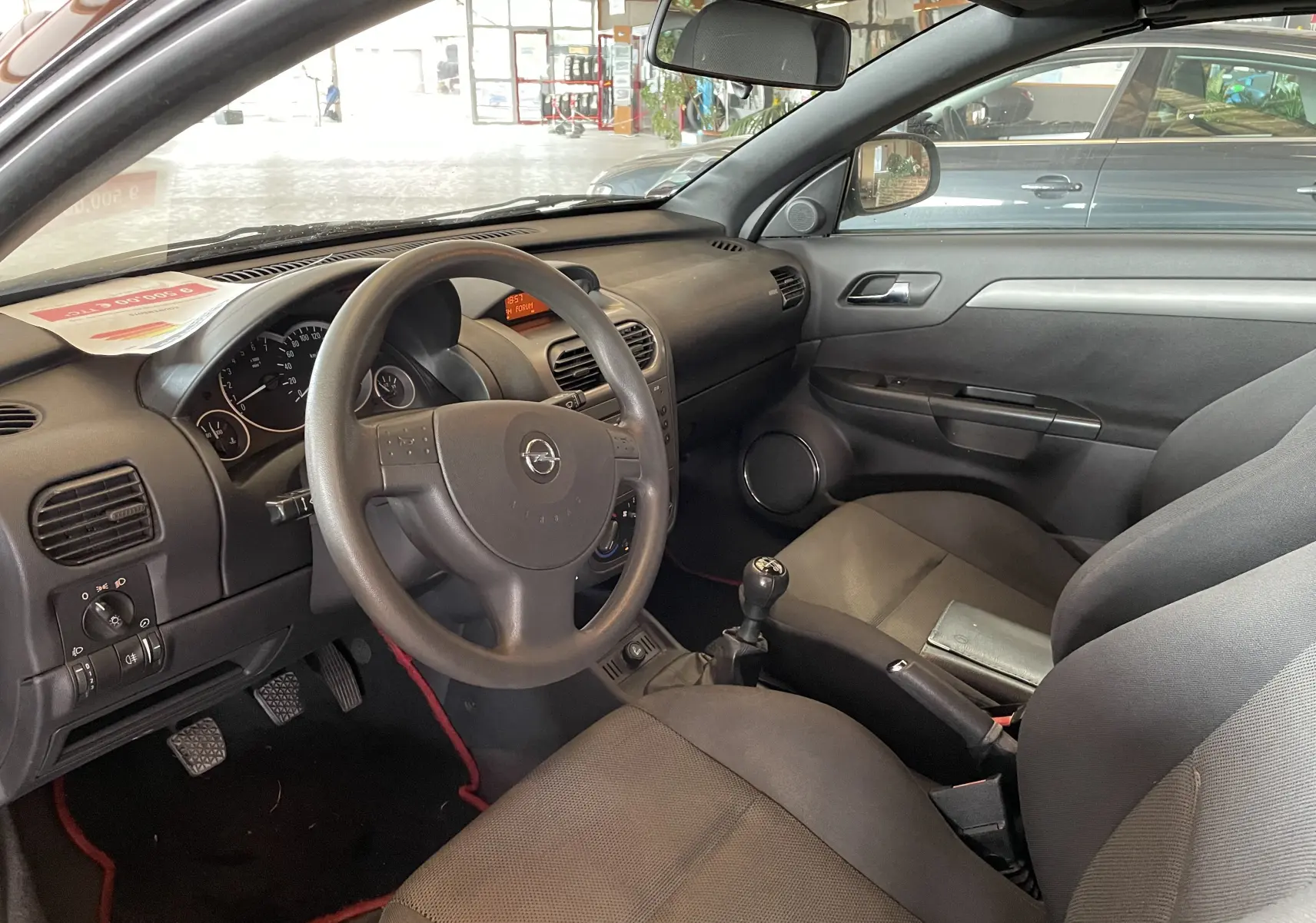 Intérieur de l'Opel Tigra Twintop 2006 vu côté conducteur, avec volant, tableau de bord et sièges gris.