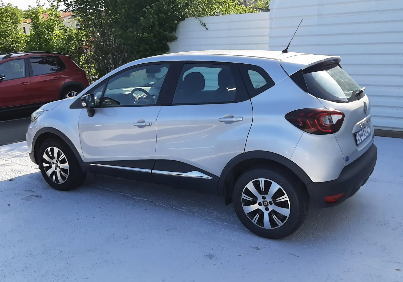 Coffre ouvert vu de l'arrière d'un Renault Captur gris platine, montrant l'espace de chargement et les sièges arrière.