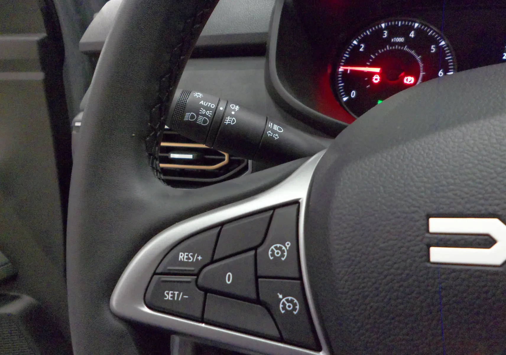 Gros plan sur le volant noir du Dacia Jogger 2025, montrant les commandes de régulateur de vitesse et le compteur partiellement visible.