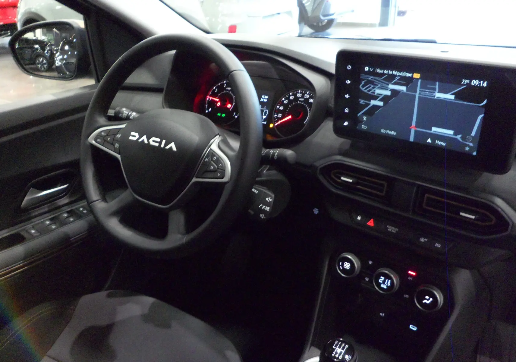 Intérieur du Dacia Jogger TCe 110 gris, vue du poste de conduite avec volant multifonction et écran tactile GPS.