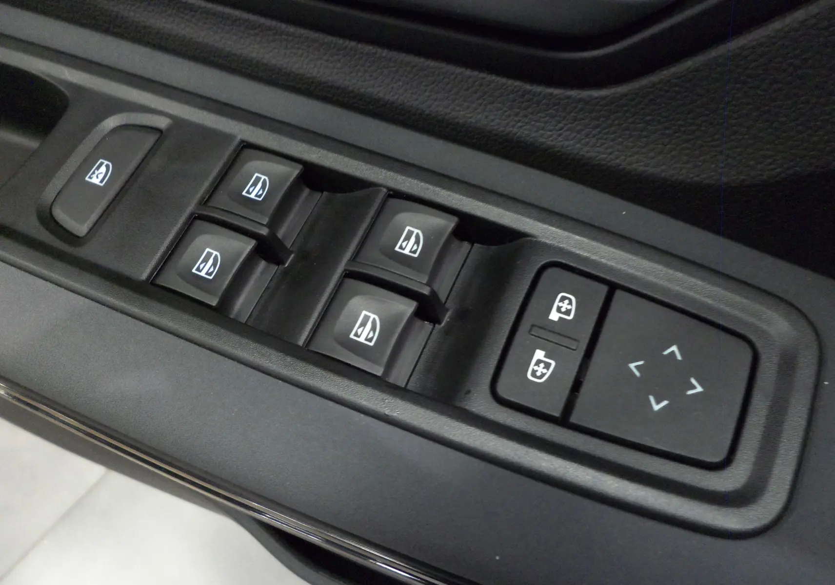 Gros plan sur les commandes électriques des vitres et rétroviseurs du côté gauche d'un Dacia Jogger gris urbain 2025.