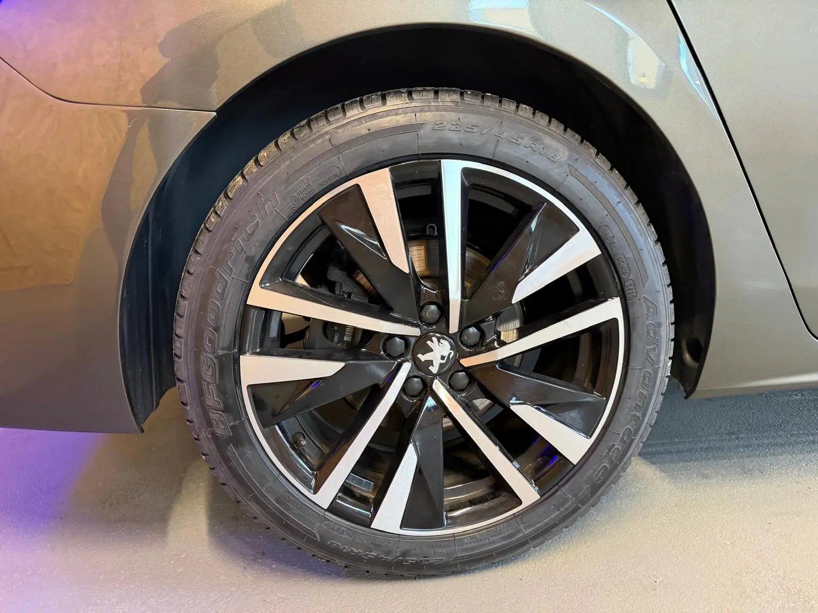 Gros plan sur la jante alu bicolore noire et argentée du côté arrière droit d'une Peugeot 508 gris métallisé.