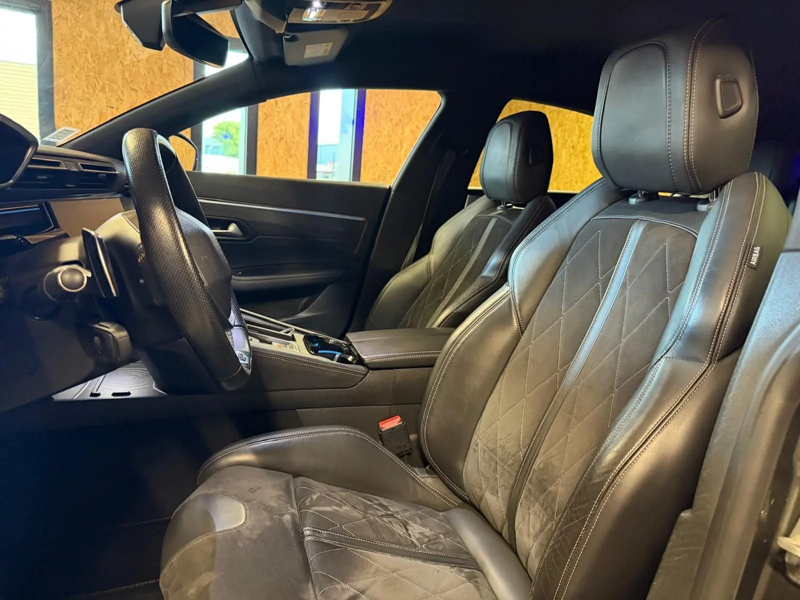 Vue intérieure côté conducteur de la Peugeot 508 gris, avec sièges cuir noir et Alcantara, volant cuir et console centrale.