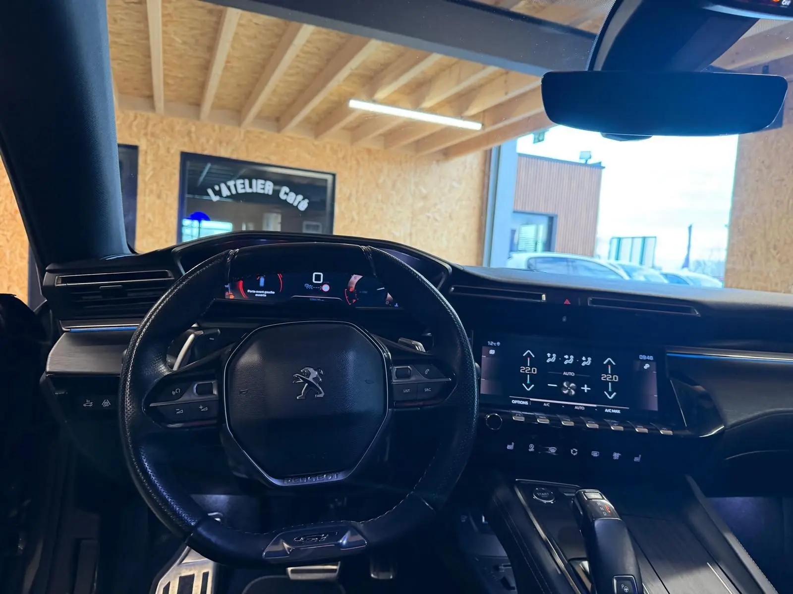 Vue intérieure centrée sur le volant cuir et tableau de bord numérique de la Peugeot 508 gris, avec écran tactile et commandes.