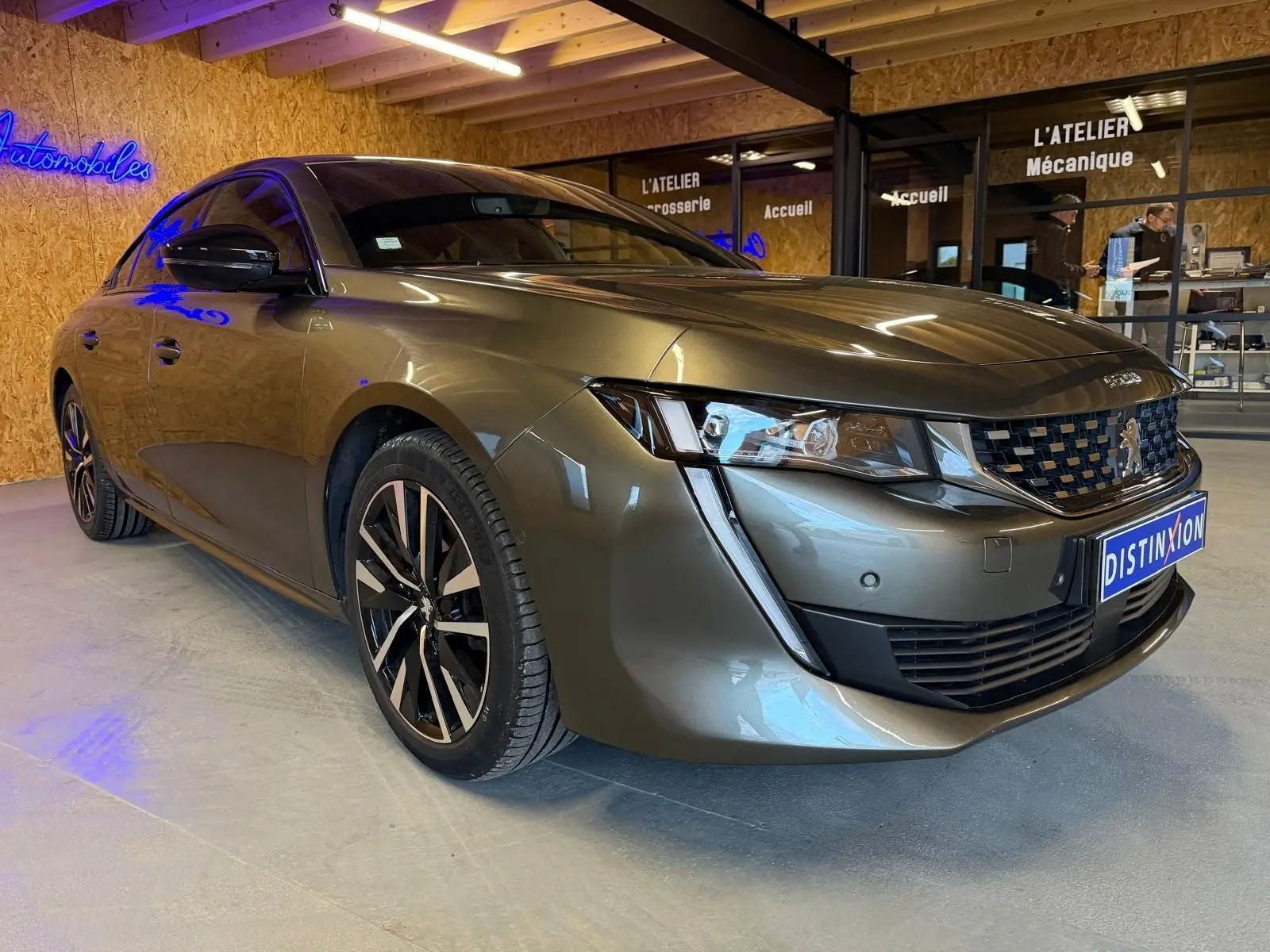 Peugeot 508 gris métallisé vue 3/4 avant droit avec jantes alliage et calandre chromée en intérieur showroom.