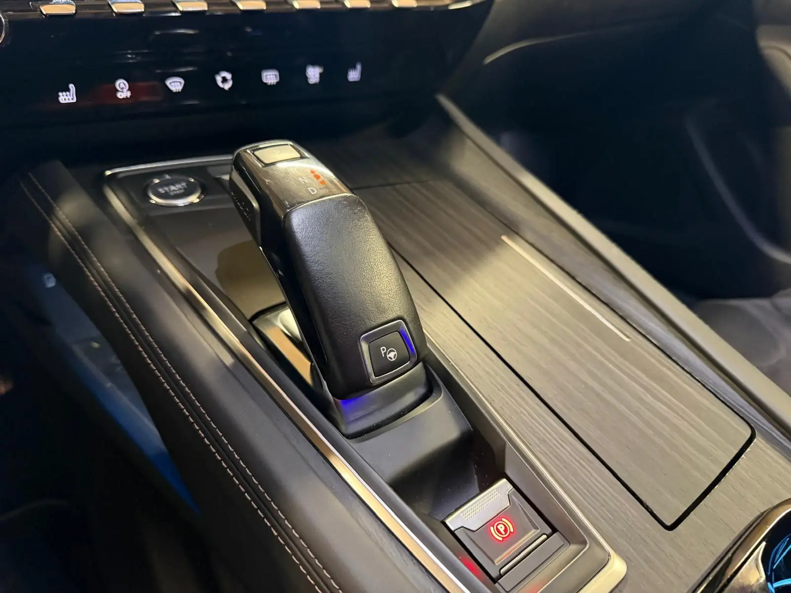 Gros plan sur la console centrale cuir et bois avec levier de vitesses automatique et bouton frein de parking Peugeot 508 gris.