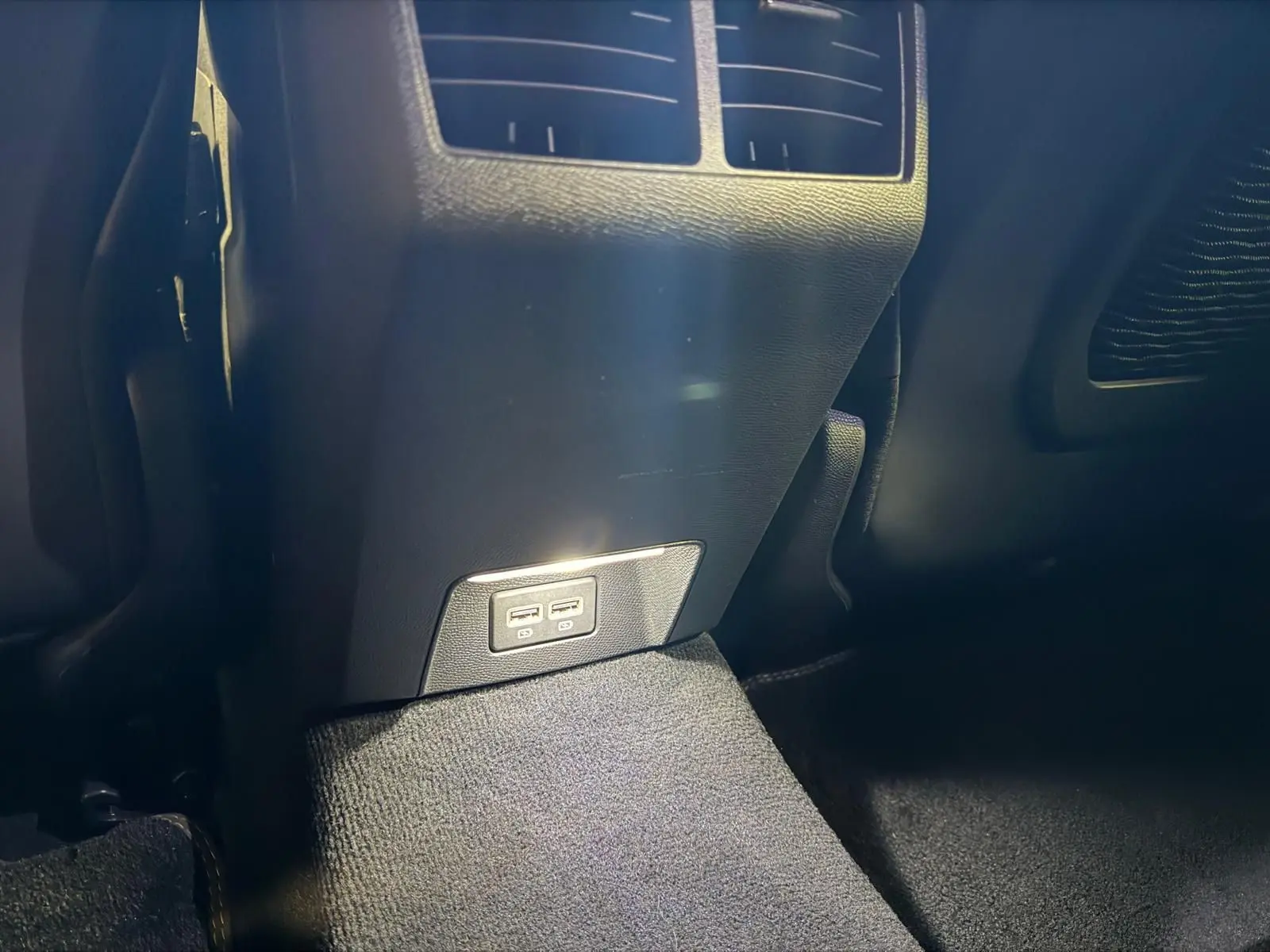 Prise USB double arrière sur console centrale noire dans Peugeot 508 gris, vue rapprochée du bas intérieur.