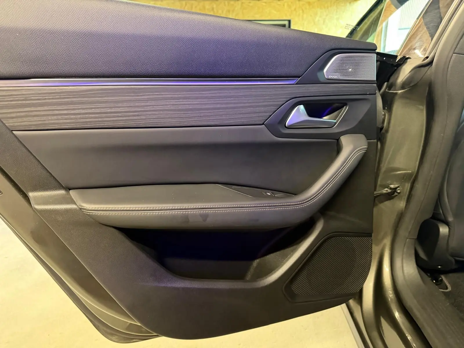 Vue intérieure côté gauche de la porte arrière grise d'une Peugeot 508 II avec insert bois et haut-parleur Focal.