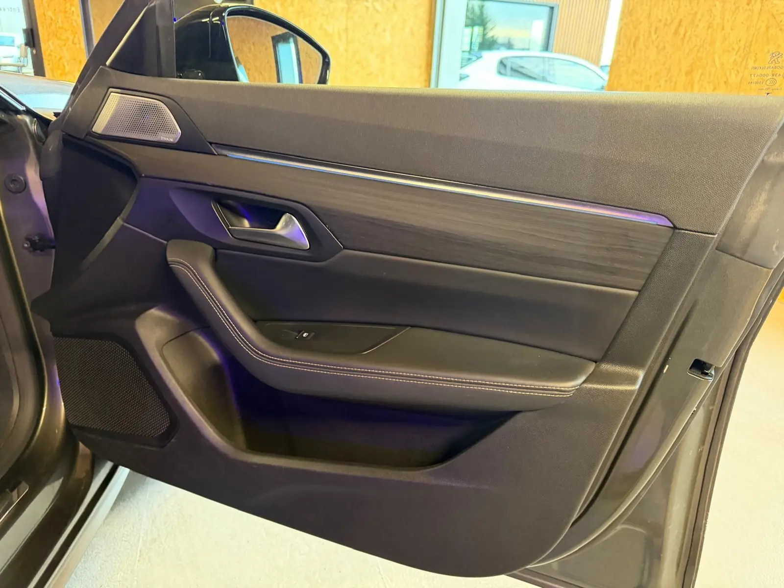 Vue intérieure côté gauche de la porte avant grise du Peugeot 508 II avec insert bois et commande de vitre électrique.