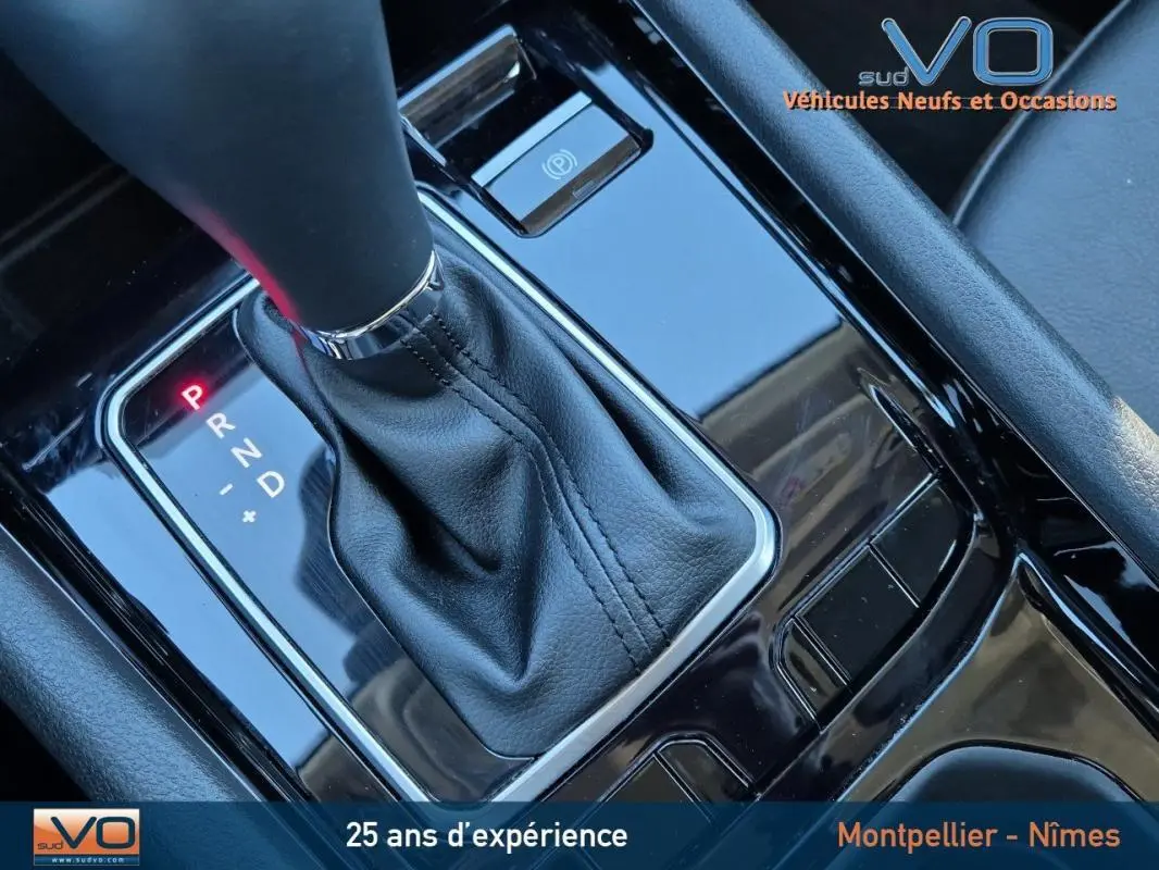 Gros plan sur la console centrale noire brillante du Jeep Compass 2024 avec levier de vitesses automatique et frein à main électrique.