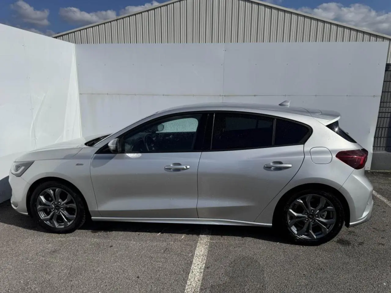Vue de profil côté gauche de la Ford Focus IV ST-Line X gris Moondust métallisé avec jantes alliage 17 pouces.