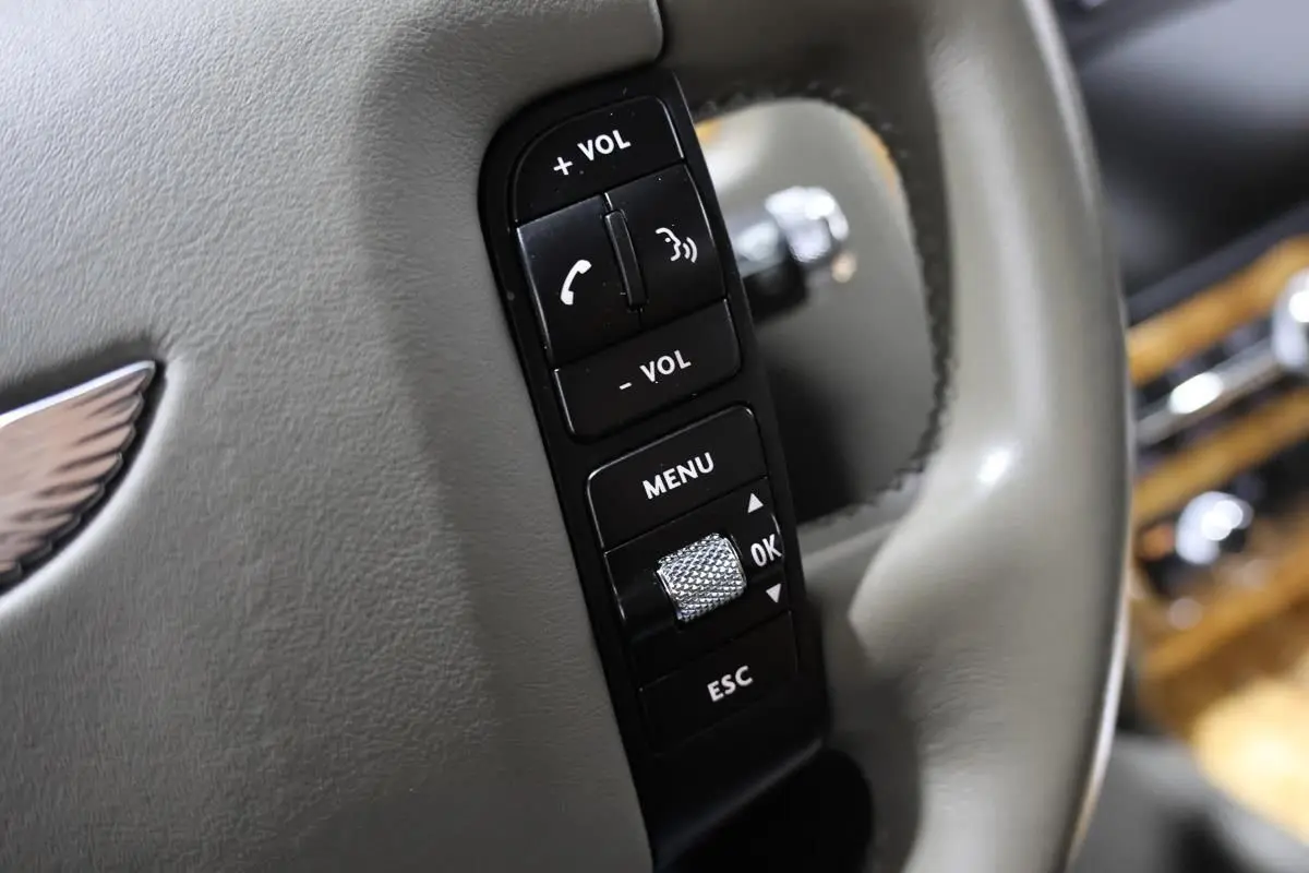 Gros plan sur les commandes noires du volant en cuir gris clair d'une Bentley Continental Flying Spur 2006.