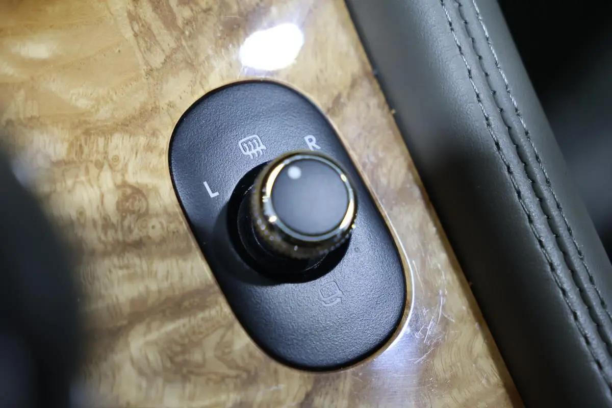 Gros plan sur le bouton de réglage des rétroviseurs sur une console en bois clair d’une Bentley Continental Flying Spur 2006.