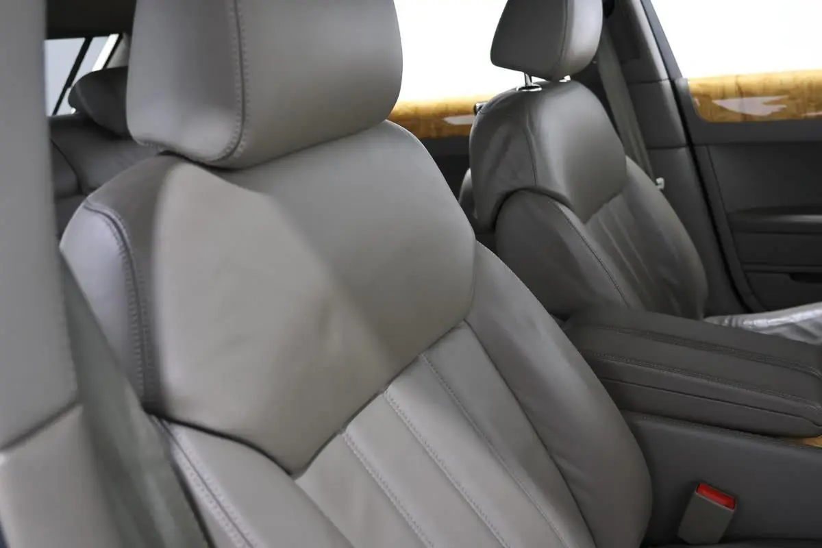 Gros plan sur les sièges avant en cuir gris clair de la Bentley Continental Flying Spur, avec inserts bois en arrière-plan.