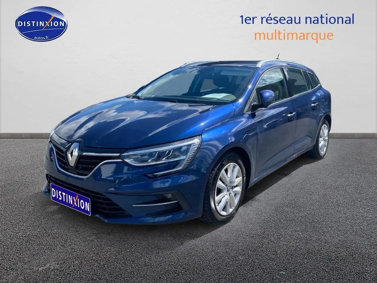 Renault Mégane IV Estate bleu en 3/4 avant droit, avec jantes alu et calandre chromée visible.