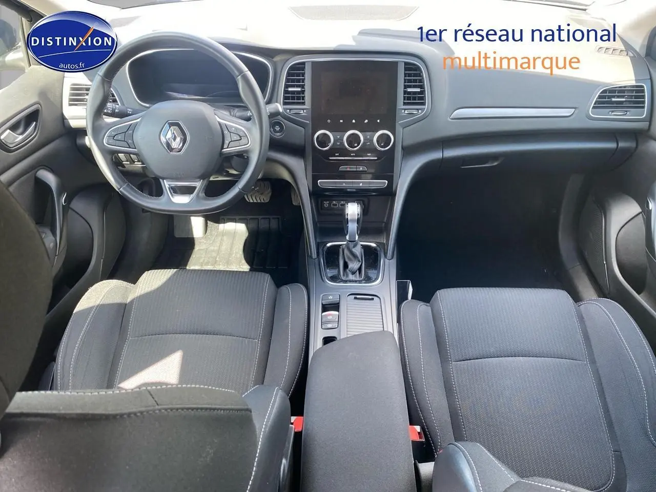 Vue intérieure avant de la Renault Mégane IV Estate 1.6 e-tech, avec tableau de bord noir et sièges tissu gris foncé.
