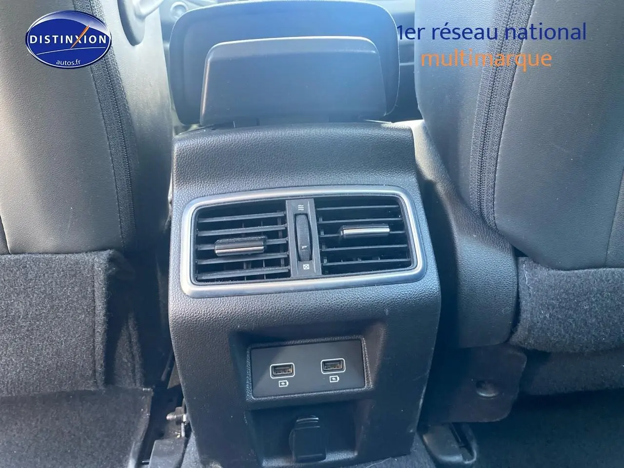 Vue rapprochée de la console arrière noire avec bouches d’aération et deux ports USB dans une Renault Mégane IV Estate bleue.