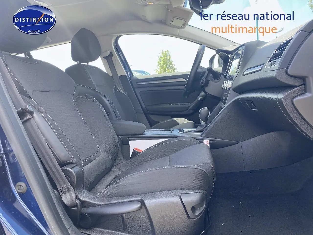 Vue intérieure côté gauche montrant les sièges avant gris foncé et la console centrale d'une Renault Mégane IV Estate bleue.