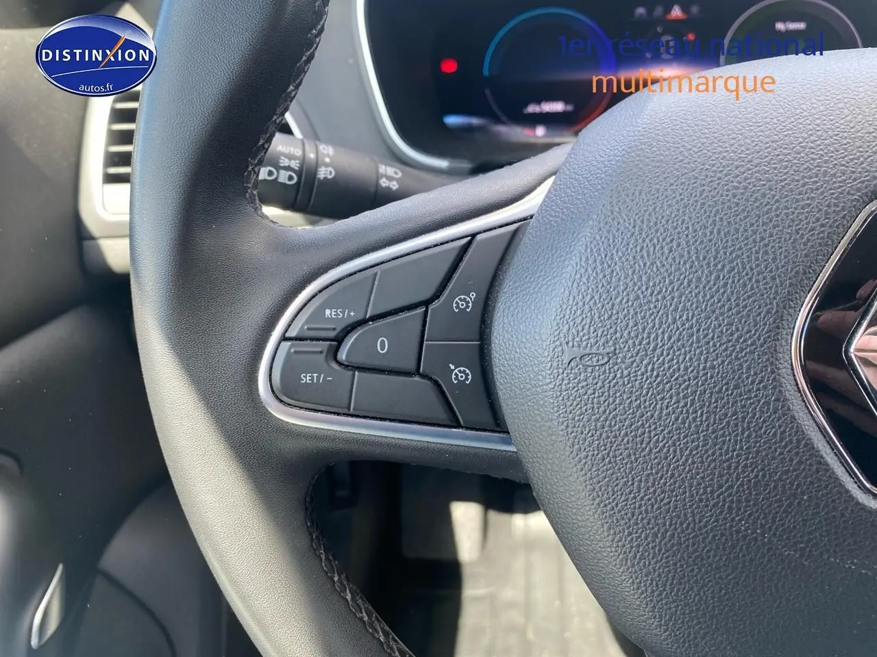 Gros plan sur le volant multifonction noir de la Renault Mégane IV Estate avec commandes de régulateur de vitesse.