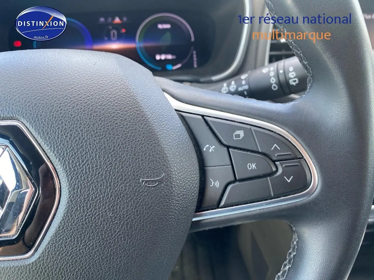 Gros plan sur le volant multifonction noir de la Renault Mégane IV Estate, avec commandes intégrées et tableau de bord numérique en arrière-plan.