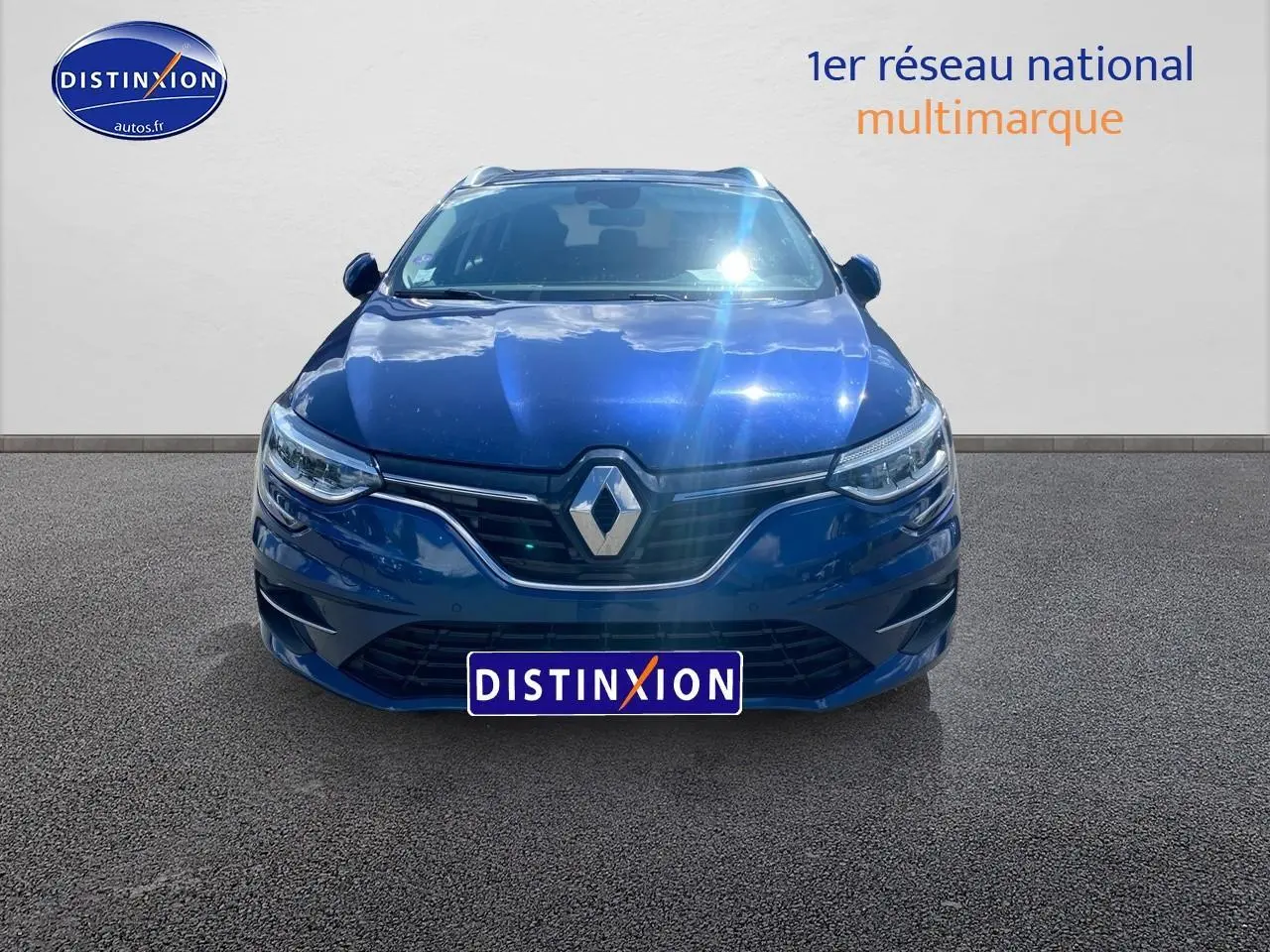 Vue avant d'une Renault Mégane IV Estate bleu électrique, avec calandre chromée et phares LED allumés.