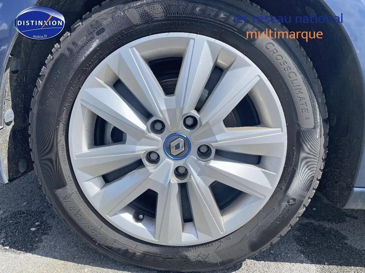 Gros plan sur la jante alu argentée avec logo Renault au centre d'une Renault Mégane IV Estate bleu.