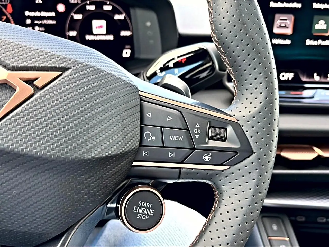 Gros plan sur le volant cuir perforé et les commandes multifonctions du CUPRA Terramar 2026, intérieur noir et cuivre.