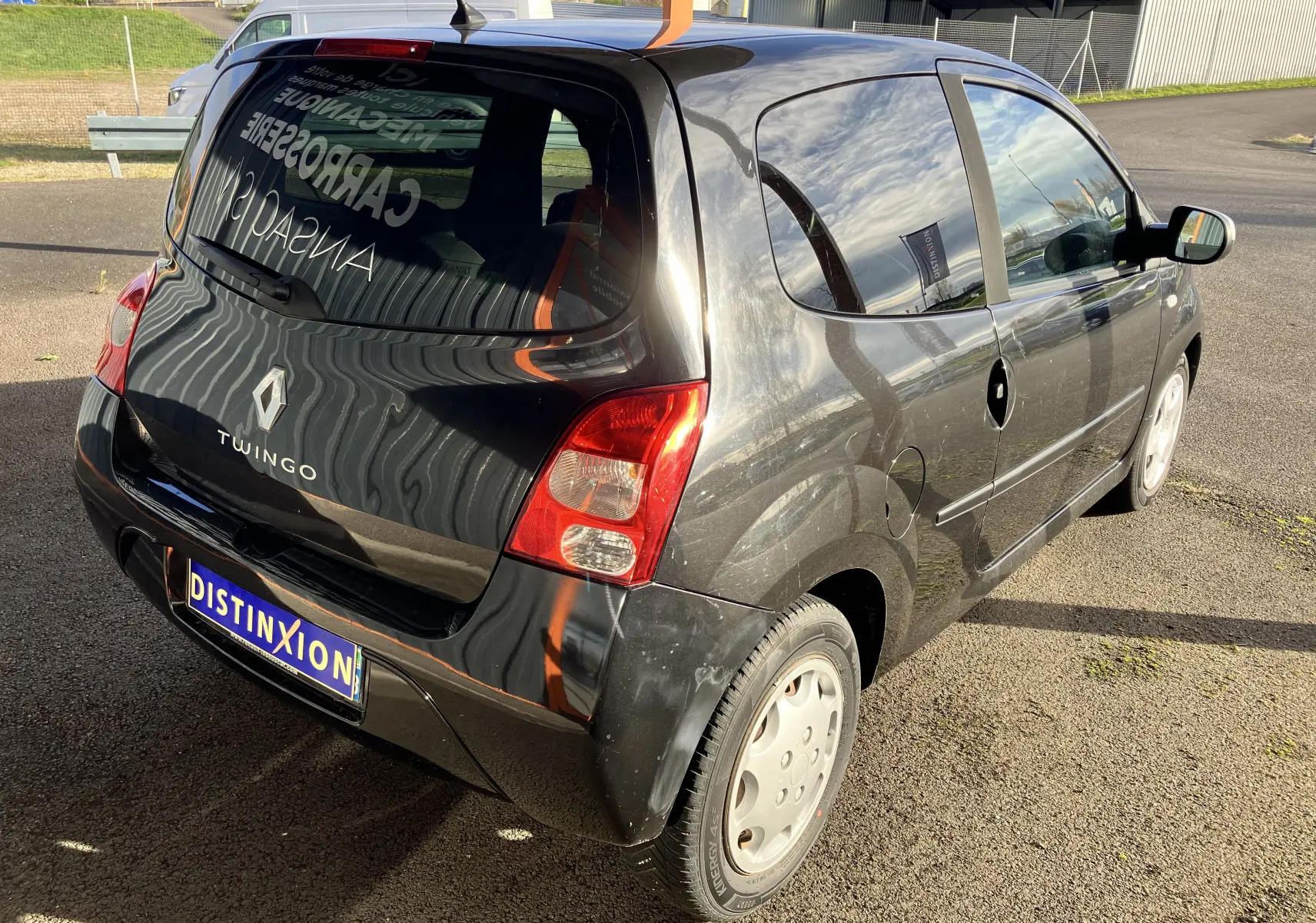 Vue 3/4 arrière droite d'une Renault Twingo II noire de 2011 avec feux arrière rouges et jantes acier simples.