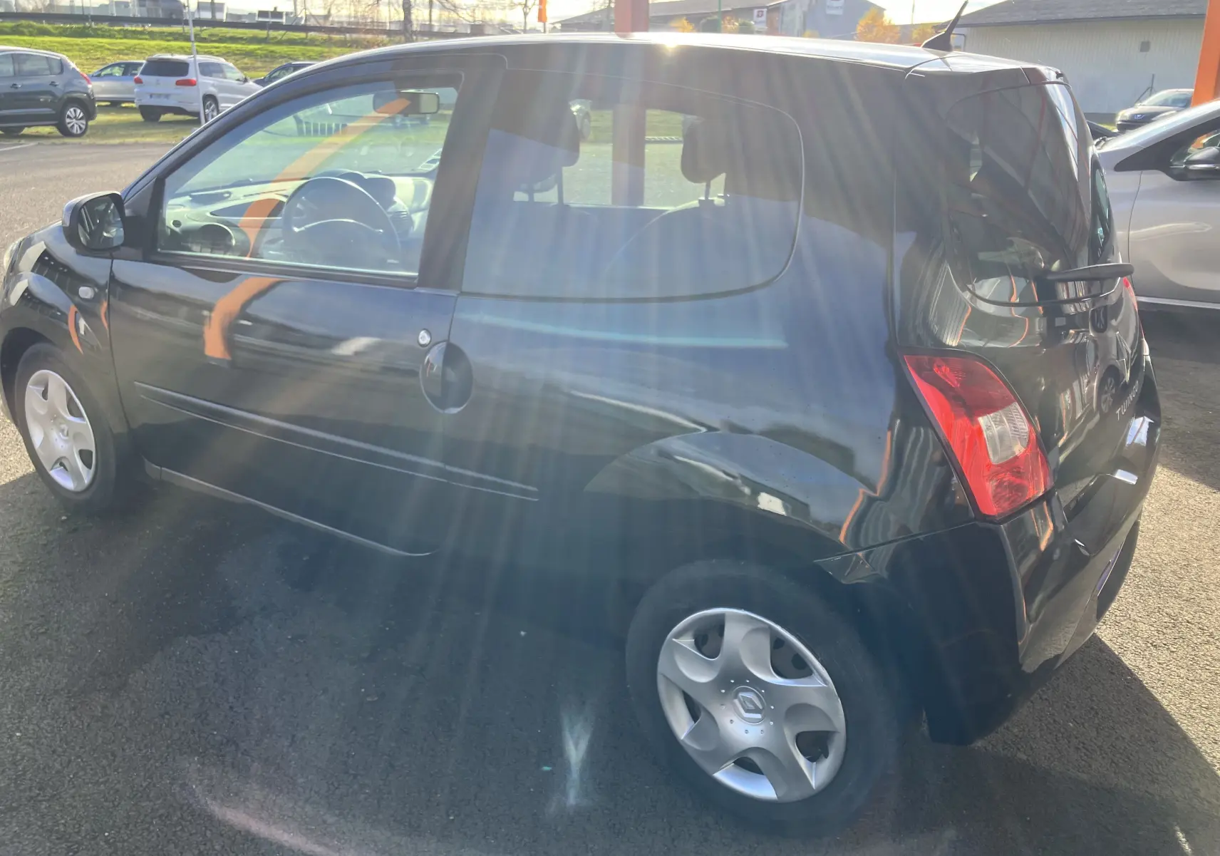 Vue latérale côté gauche d'une Renault Twingo II noire de 2011 avec jantes alliage et feux arrière visibles.