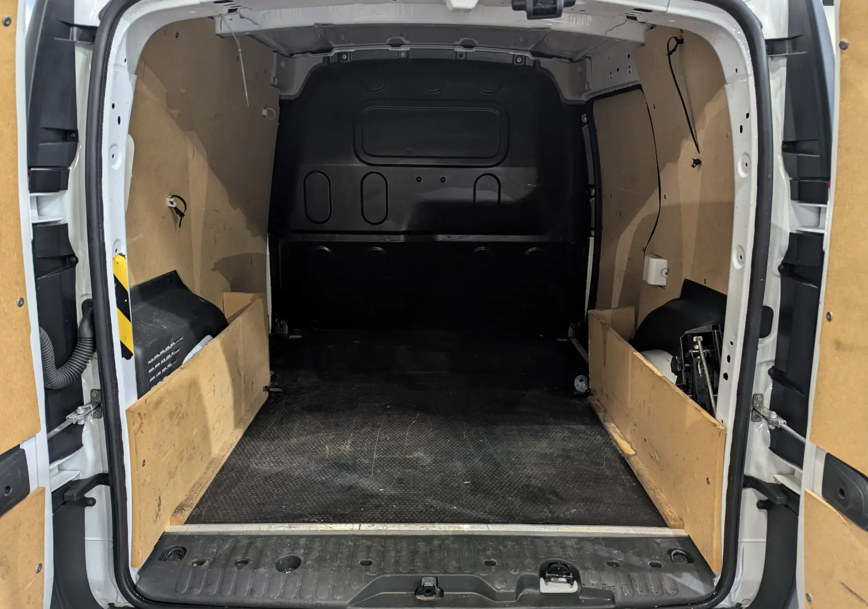 Vue arrière ouverte du Renault Kangoo Express blanc minéral, montrant l'espace de chargement vide avec parois en bois.