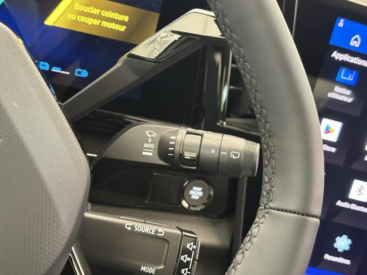 Gros plan sur le volant cuir et la commande de boîte auto du Renault Austral blanc, avec écran tactile et bouton start visible.